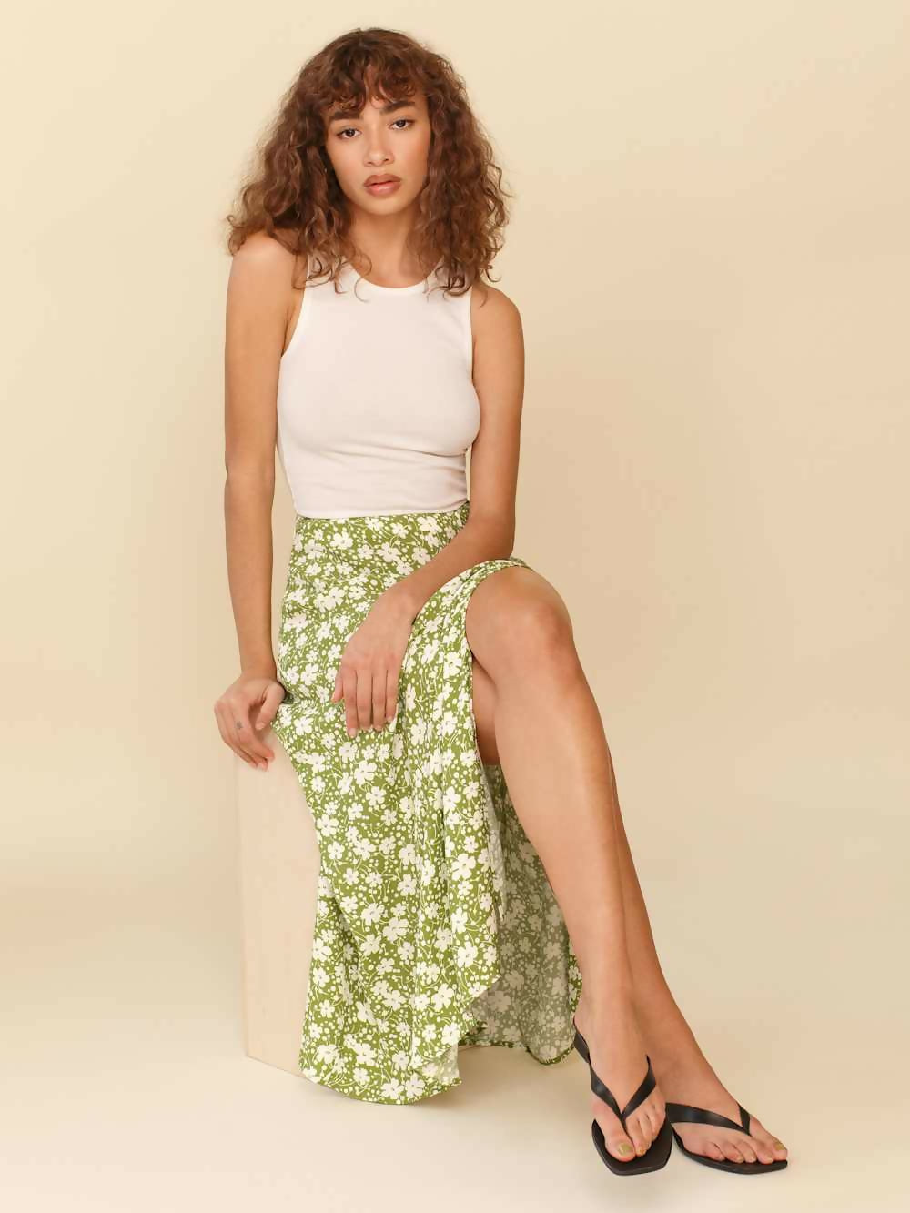 Woman wearing white sleeveless tank top and green floral midi skirt with side slit — Endless | Endless UAE