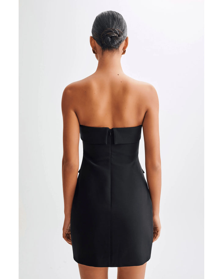 Rear view of woman wearing black strapless fitted mini dress with center back zipper and sleek silhouette — Meshki | Endless UAE