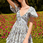 Woman wearing blue floral cotton mini dress with puff sleeves and cream tote bag — Agua by Agua Bendita | Endless UAE
