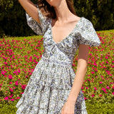 Woman wearing blue floral cotton mini dress with puff sleeves and cream tote bag — Agua by Agua Bendita | Endless UAE