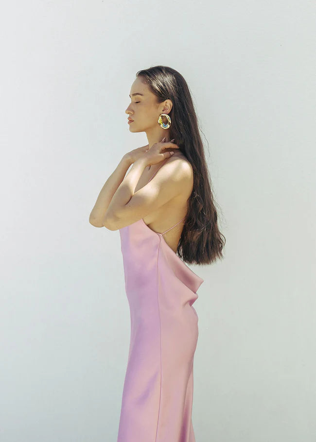 Woman wearing a pink satin slip dress with thin straps and flowing maxi length — Dvete | Endless UAE