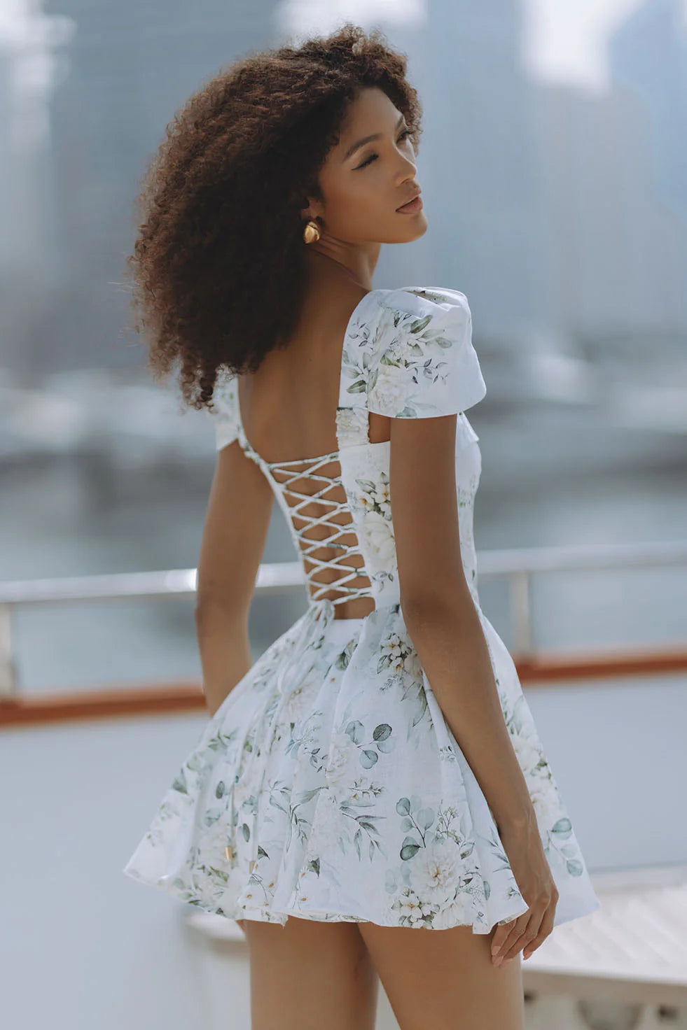 Woman wearing white floral mini dress with puff sleeves on balcony — Chic Le Frique | Endless UAE