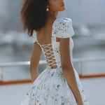 Woman wearing white floral mini dress with puff sleeves on balcony — Chic Le Frique | Endless UAE