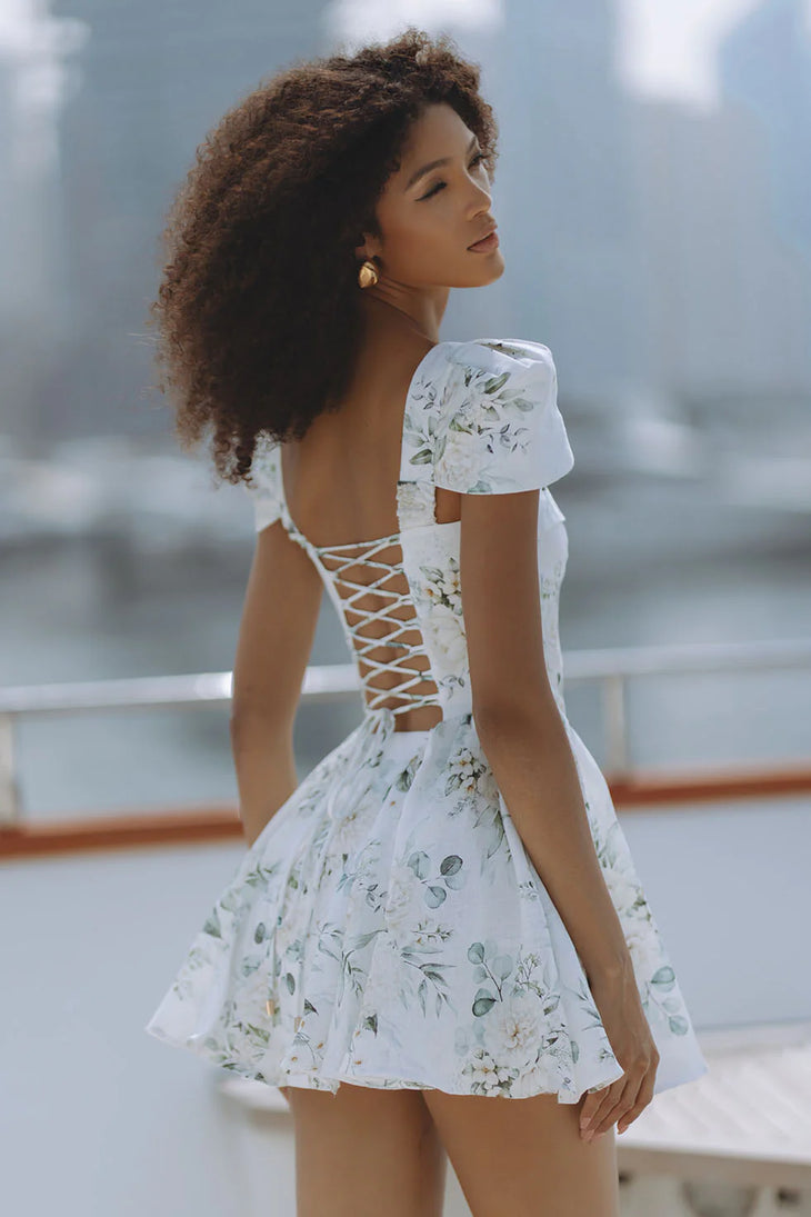 Woman wearing white floral mini dress with puff sleeves on balcony — Chic Le Frique | Endless UAE