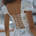 Woman wearing white floral mini dress with puff sleeves on balcony — Chic Le Frique | Endless UAE