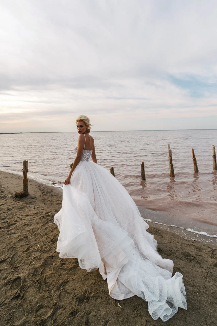 Bride in flowing white sparkle tulle wedding gown with corset bodice on beach at sunset — Romanova Atelier | Endless UAE