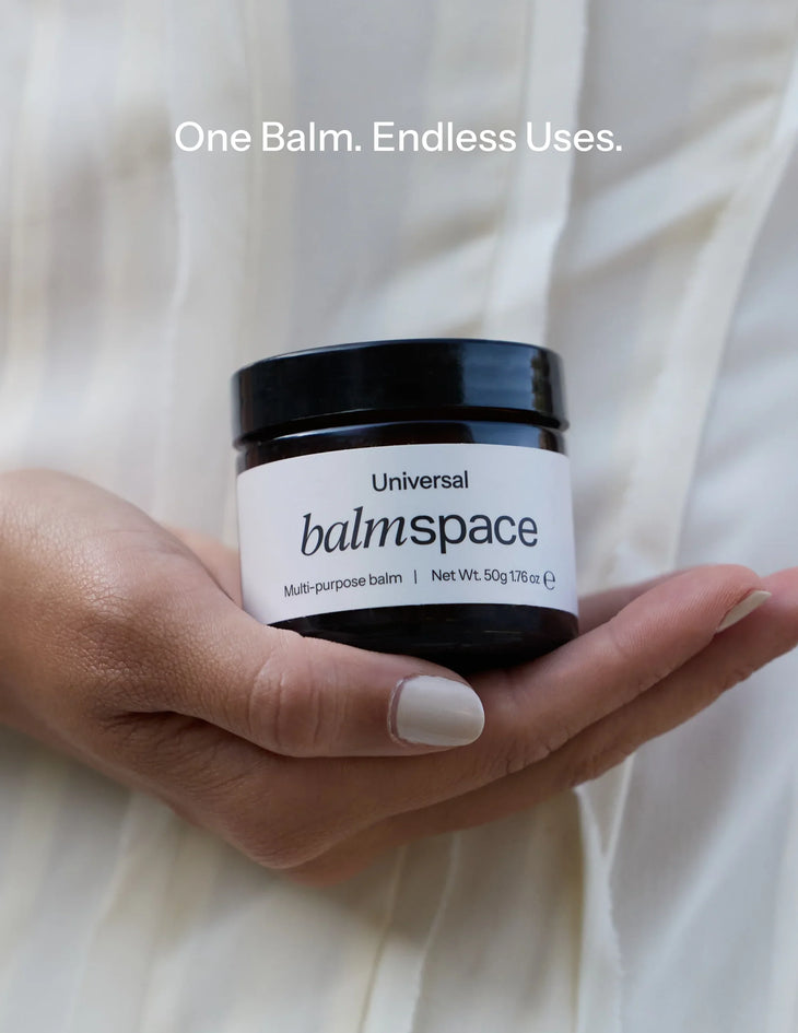 Hand holding jar of Universal Multi-Purpose Balm against white linen background — Balm Space | Endless UAE
