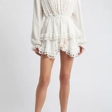 Woman wearing white eyelet cotton mini dress with long sleeves and layered skirt — LoveShackFancy | Endless UAE