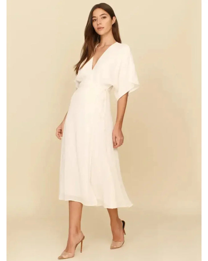 Woman wearing white midi wrap dress with V-neckline and short sleeves, paired with nude heels — Reformation | Endless UAE