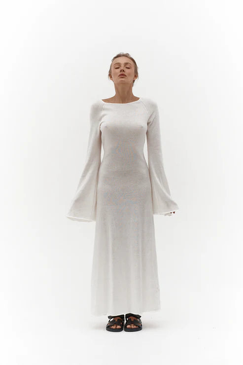 Woman wearing elegant white knit maxi dress with flared sleeves against minimal background — Affluence | Endless UAE