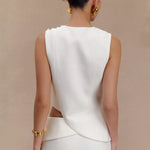 Rear view of woman wearing white sleeveless asymmetric suiting top with gold jewelry and hair in bun — Endless | Endless UAE