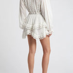 Woman wearing white eyelet cotton mini dress with long sleeves and layered skirt — LoveShackFancy | Endless UAE