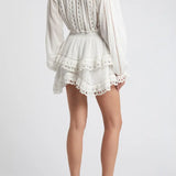 Woman wearing white eyelet cotton mini dress with long sleeves and layered skirt — LoveShackFancy | Endless UAE
