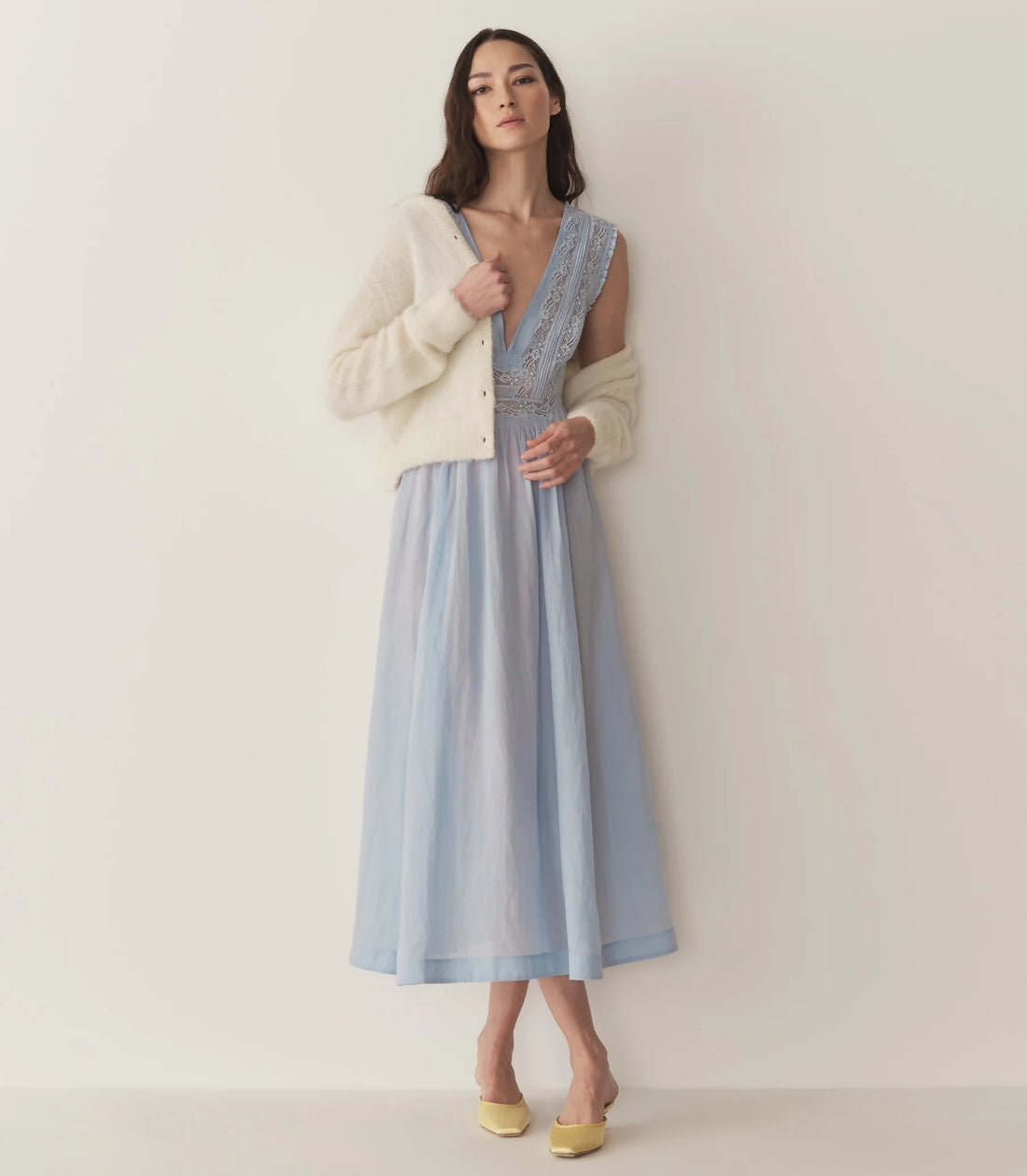 Woman wearing light blue Victoria Midi Dress with lace bodice and cream cardigan — Doen | Endless UAE