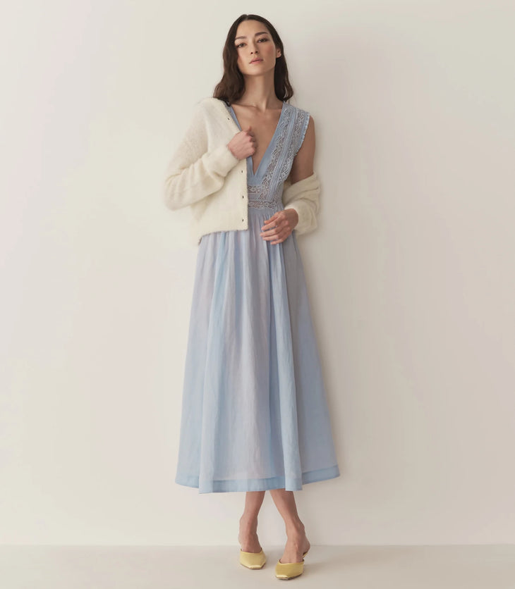 Woman wearing light blue Victoria Midi Dress with lace bodice and cream cardigan — Doen | Endless UAE