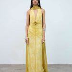 Woman wearing yellow halter maxi dress with deep V-neckline and circular buckle detail — Endless | Endless UAE