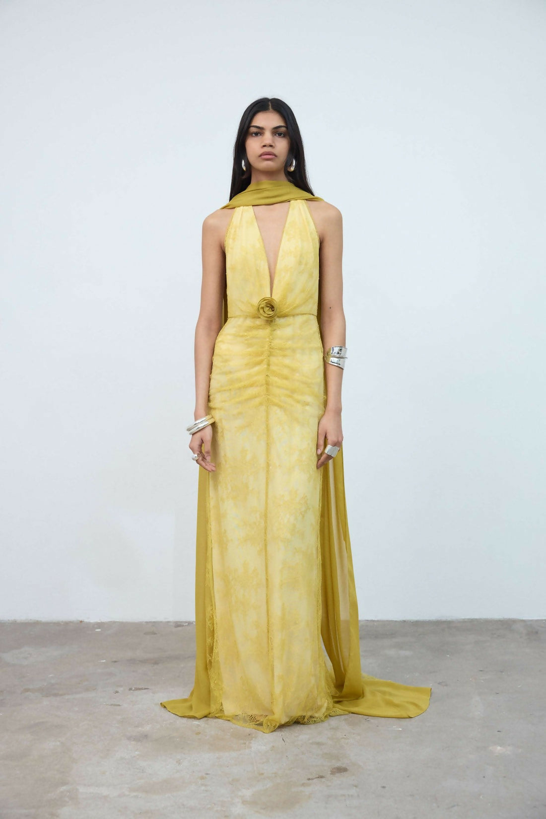 Woman wearing yellow halter maxi dress with deep V-neckline and circular buckle detail — Endless | Endless UAE