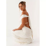 Woman wearing white off-shoulder textured maxi dress with cutout waist detail, viewed from back — Peppermayo | Endless UAE