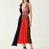 Woman wearing pleated asymmetric maxi dress in black, blush pink and red with black ankle strap heels — Victoria Beckham | Endless UAE