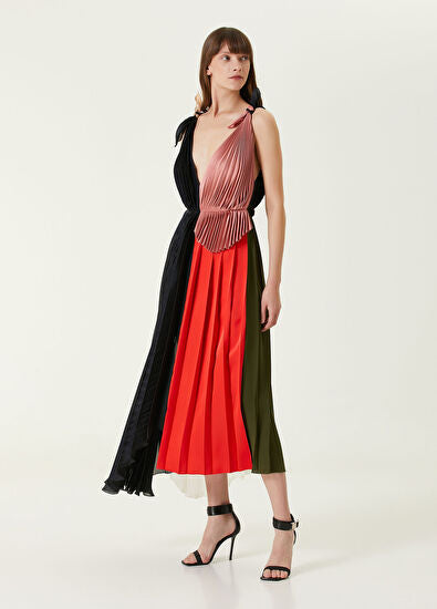 Woman wearing pleated asymmetric maxi dress in black, blush pink and red with black ankle strap heels — Victoria Beckham | Endless UAE