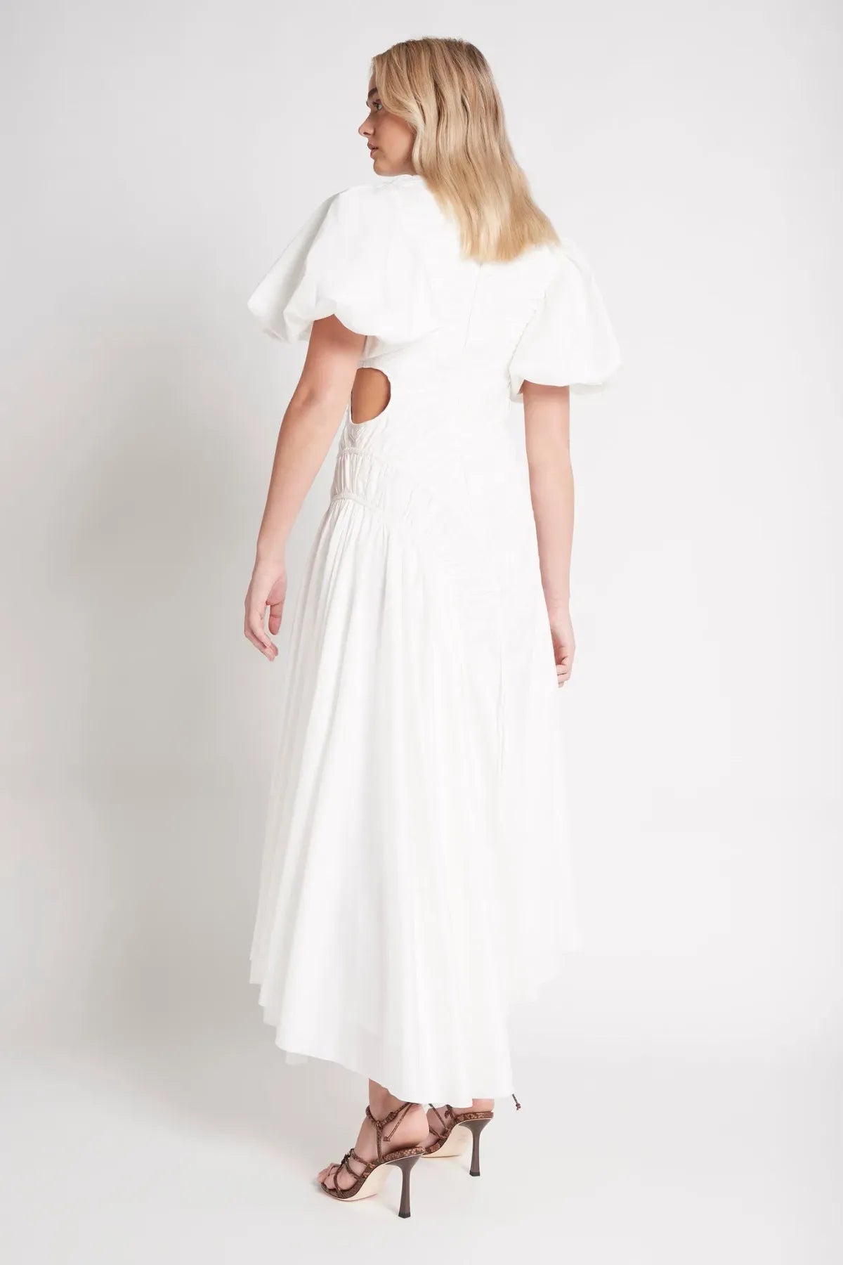 Woman wearing white Siren Drawstring Midi Dress with puffed sleeves and green strappy heels — Aje | Endless UAE