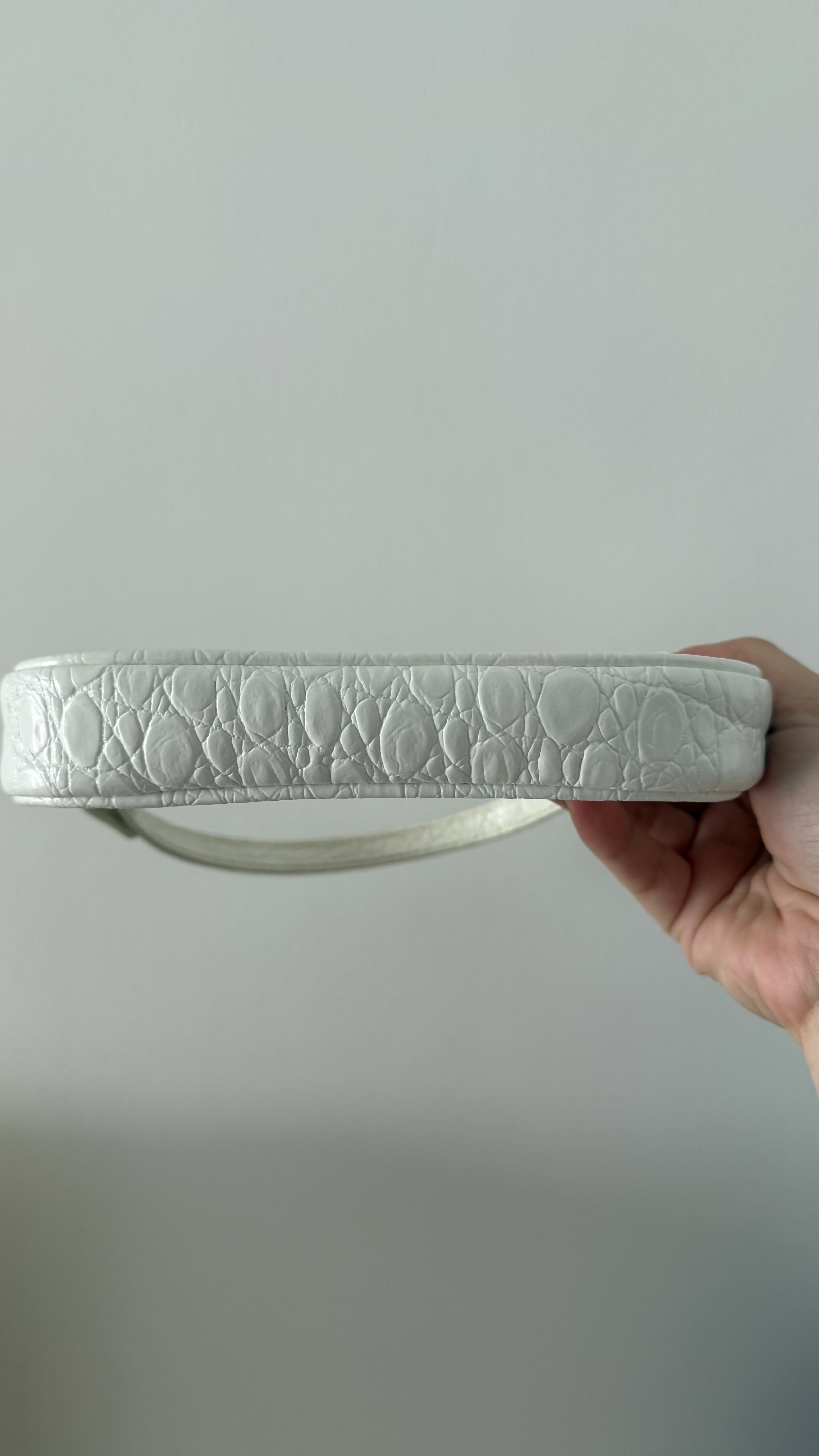 White quilted mini shoulder bag with silver hardware held up against neutral background — By Far | Endless UAE