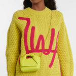 Woman wearing yellow cable knit sweater carrying a small lime green leather Twister Nano crossbody bag on gold chain strap — JW Anderson | Endless UAE