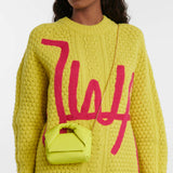 Woman wearing yellow cable knit sweater carrying a small lime green leather Twister Nano crossbody bag on gold chain strap — JW Anderson | Endless UAE