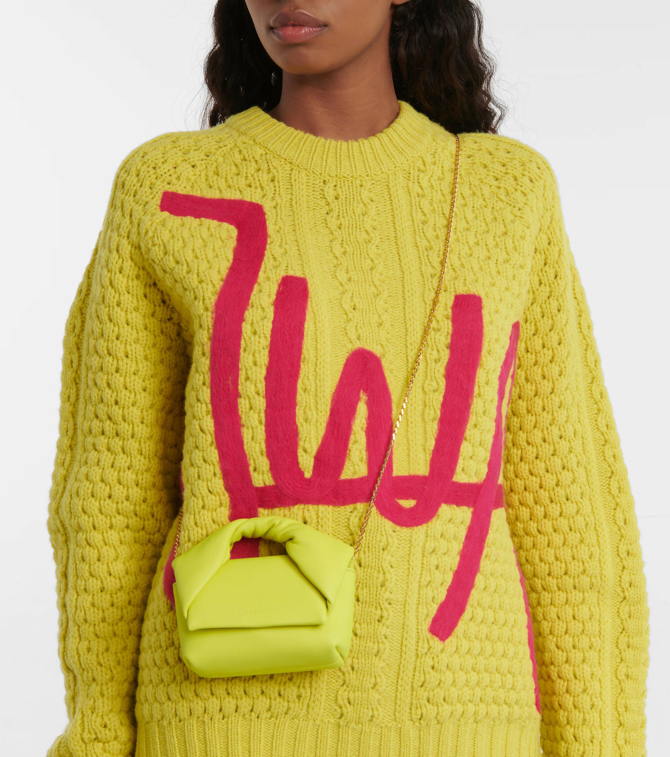 Woman wearing yellow cable knit sweater carrying a small lime green leather Twister Nano crossbody bag on gold chain strap — JW Anderson | Endless UAE