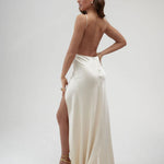 Elegant ivory satin backless maxi dress with high slit and thin straps, worn with gold strappy heels — By Keara | Endless UAE