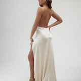 Elegant ivory satin backless maxi dress with high slit and thin straps, worn with gold strappy heels — By Keara | Endless UAE