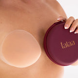 Reusable silicone nipple covers in nude shade with burgundy storage case held against skin — Talaa | Endless UAE