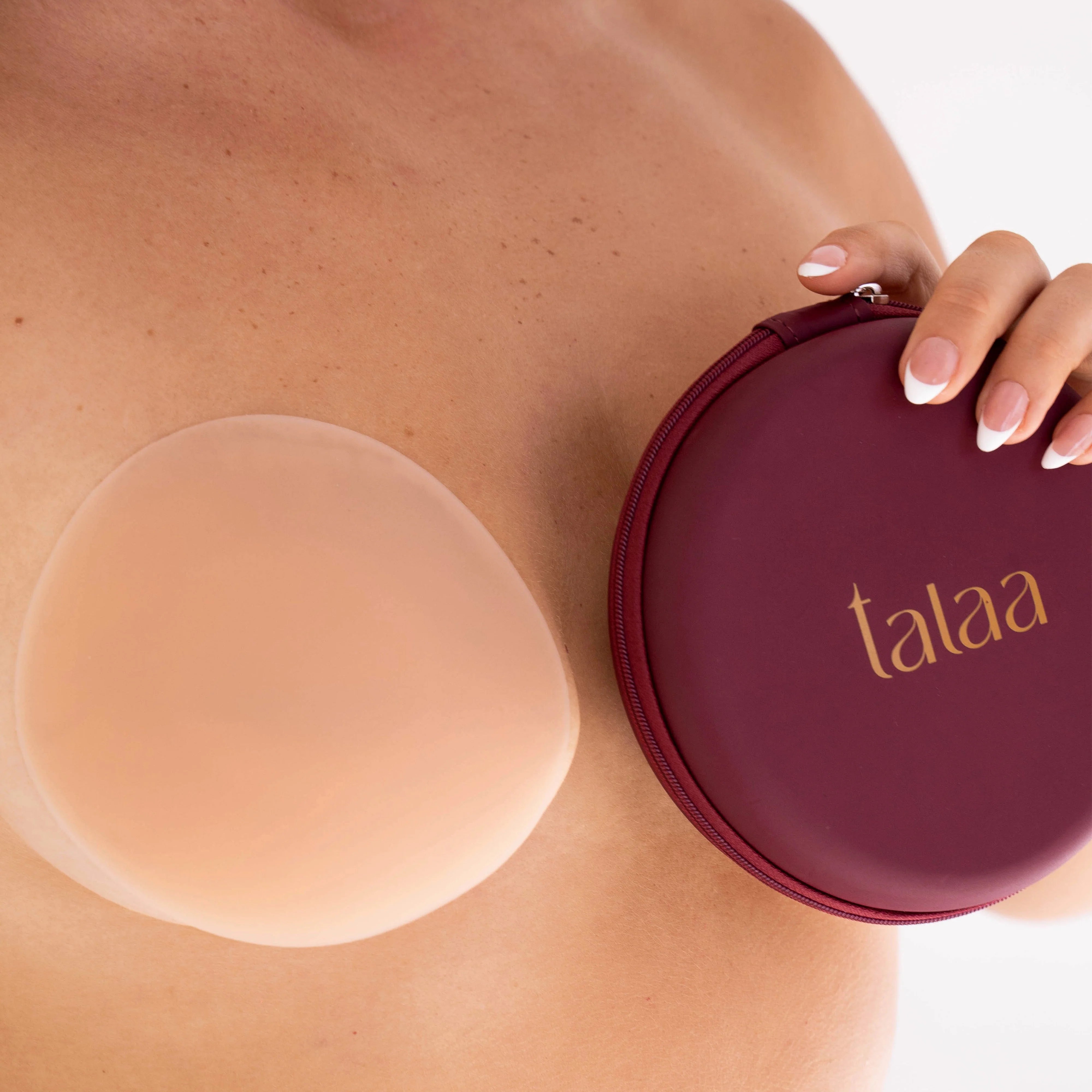 Reusable silicone nipple covers in nude shade with burgundy storage case held against skin — Talaa | Endless UAE