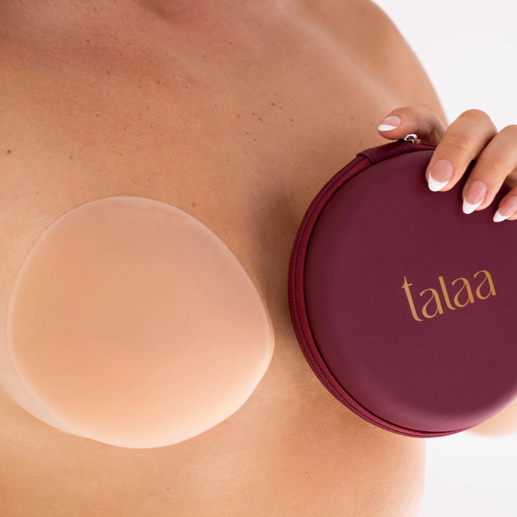 Reusable silicone nipple covers in nude shade with burgundy storage case held against skin — Talaa | Endless UAE
