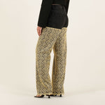 Wide-leg patterned denim pants with black wavy print on beige background, worn with black denim jacket — Quab | Endless UAE