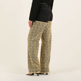 Wide-leg patterned denim pants with black wavy print on beige background, worn with black denim jacket — Quab | Endless UAE