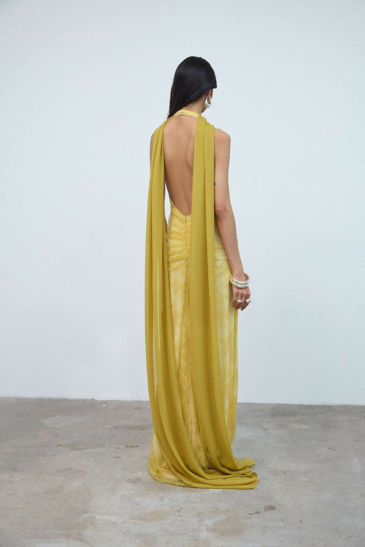 Woman wearing yellow halter maxi dress with deep V-neckline and circular buckle detail — Endless | Endless UAE