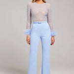 Woman wearing lavender beaded crop top with feathered cuffs and light blue wide-leg trousers — Nadine Merabi | Endless UAE
