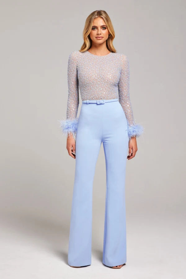 Woman wearing lavender beaded crop top with feathered cuffs and light blue wide-leg trousers — Nadine Merabi | Endless UAE