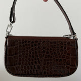 Dark brown croc-embossed mini shoulder bag with chain detail held in hand — By Far | Endless UAE
