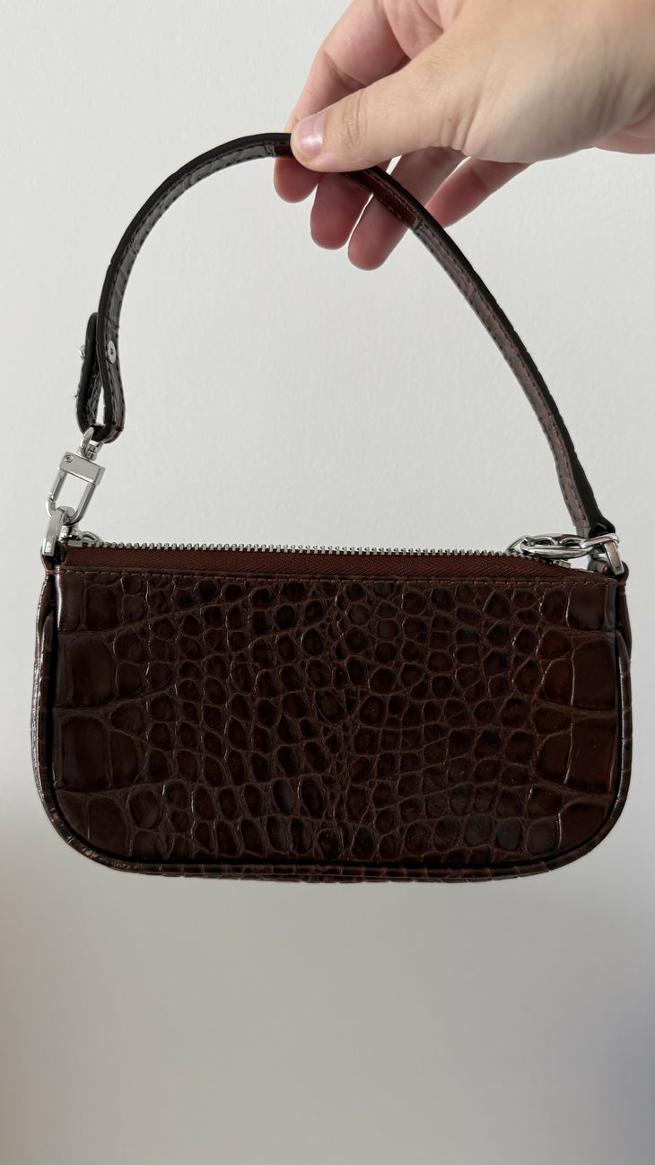 Dark brown croc-embossed mini shoulder bag with chain detail held in hand — By Far | Endless UAE