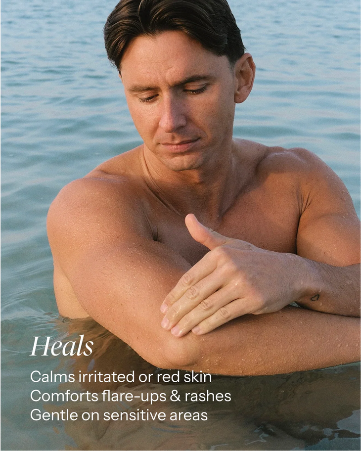 Man applying healing balm to sun-exposed skin by the water, showing soothing relief for irritated areas — Balm Space | Endless UAE