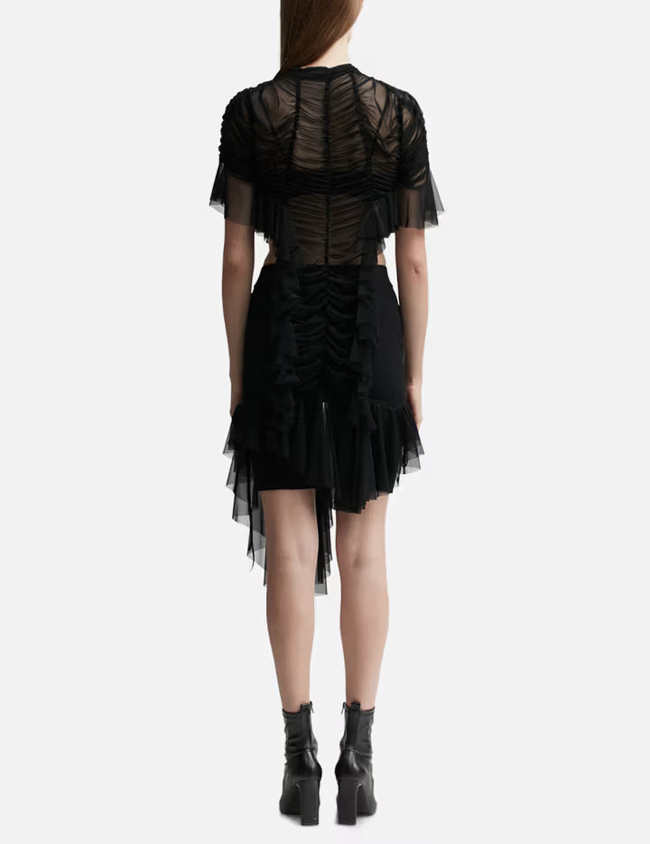 Black ruched dress with sheer tulle overlay, asymmetric hem, and short sleeves, shown from back — Ester Manas | Endless UAE