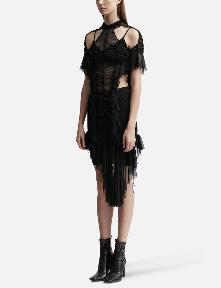 Black ruched dress with cold shoulder detail, sheer mesh panels, and asymmetric tulle hem worn with ankle boots — Ester Manas | Endless UAE