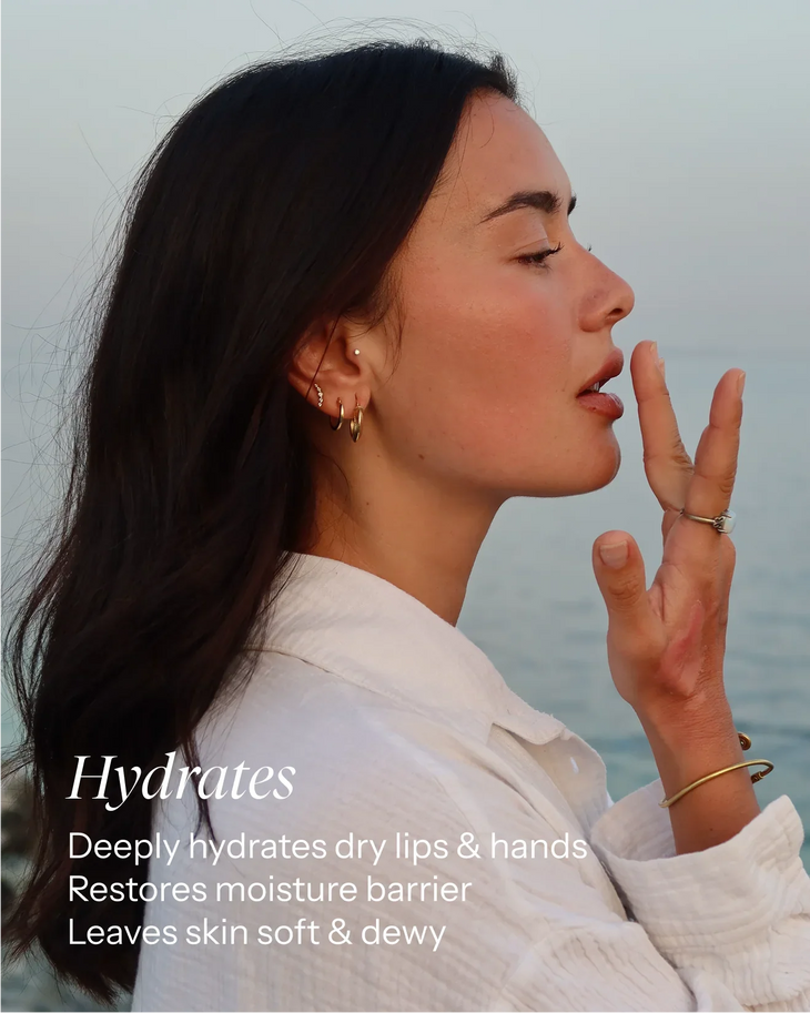 Woman applying hydrating multi-purpose balm to face showing soft dewy skin by the ocean — Balm Space | Endless UAE