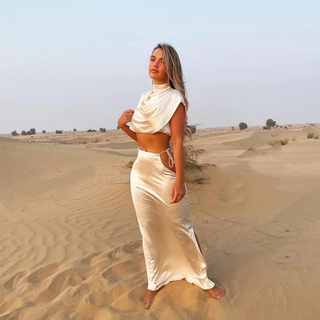 Cream Faye Co-ord Set featuring draped crop top and maxi skirt on model in desert landscape — Deme Studio | Endless UAE