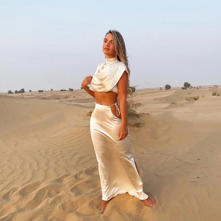Cream Faye Co-ord Set featuring draped crop top and maxi skirt on model in desert landscape — Deme Studio | Endless UAE
