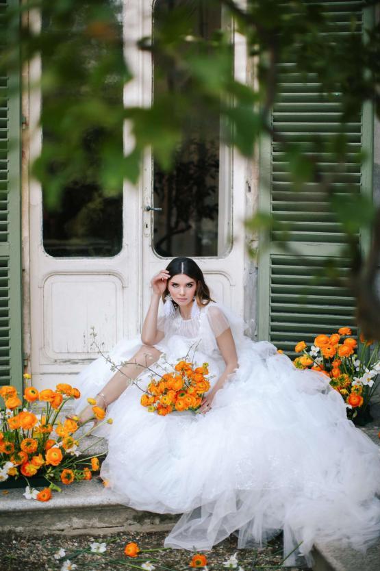 Bride in white tulle Lorenso gown seated on doorstep with orange flowers and green shutters — Blammo Biamo | Endless UAE