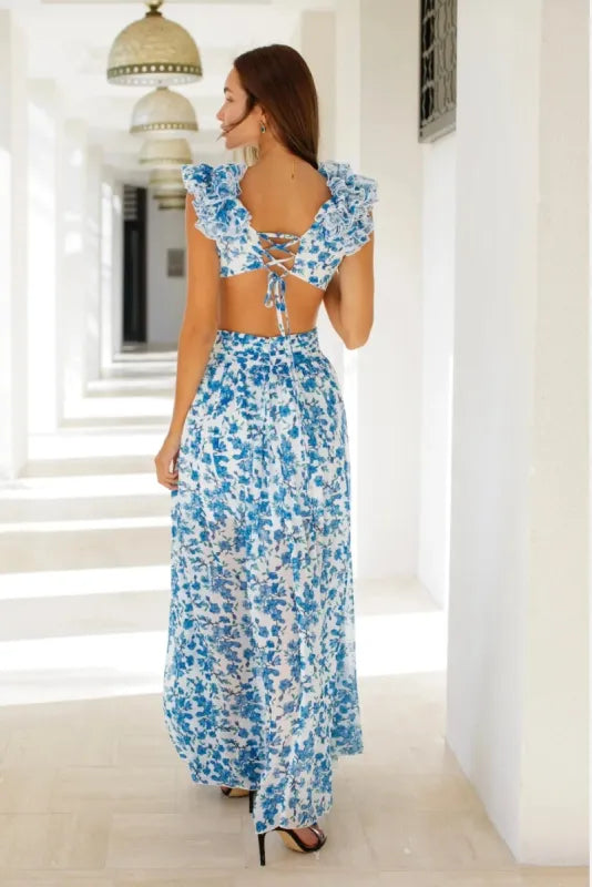 Woman wearing blue and white floral maxi dress with ruffled straps in white Mediterranean setting — Anne Louise Boutique | Endless UAE