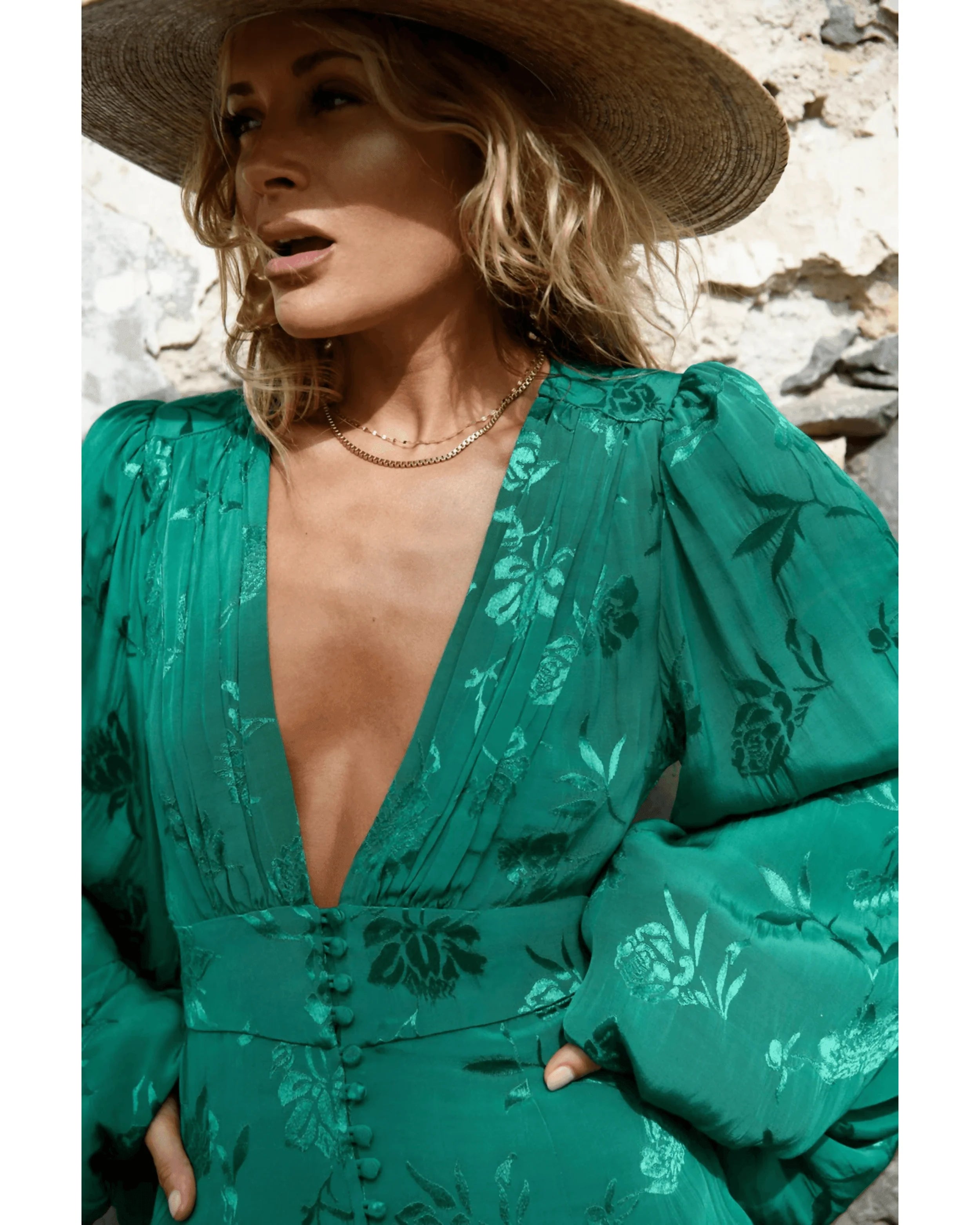 Blonde woman wearing emerald green floral jacquard dress with puff sleeves and deep V-neckline, styled with straw hat — Rat & Boa | Endless UAE